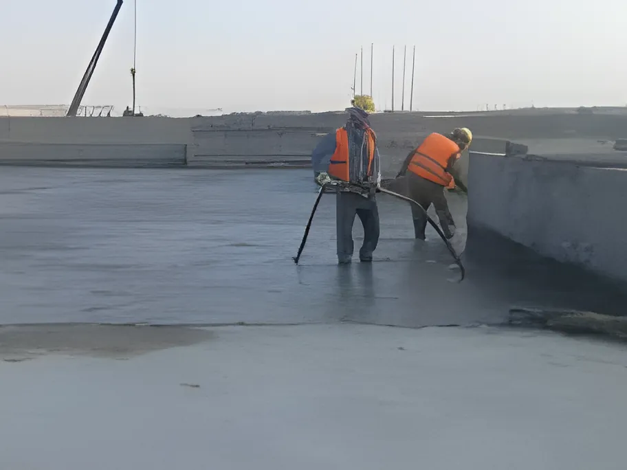 Two-man crew spraying liquid membrane across a large roof