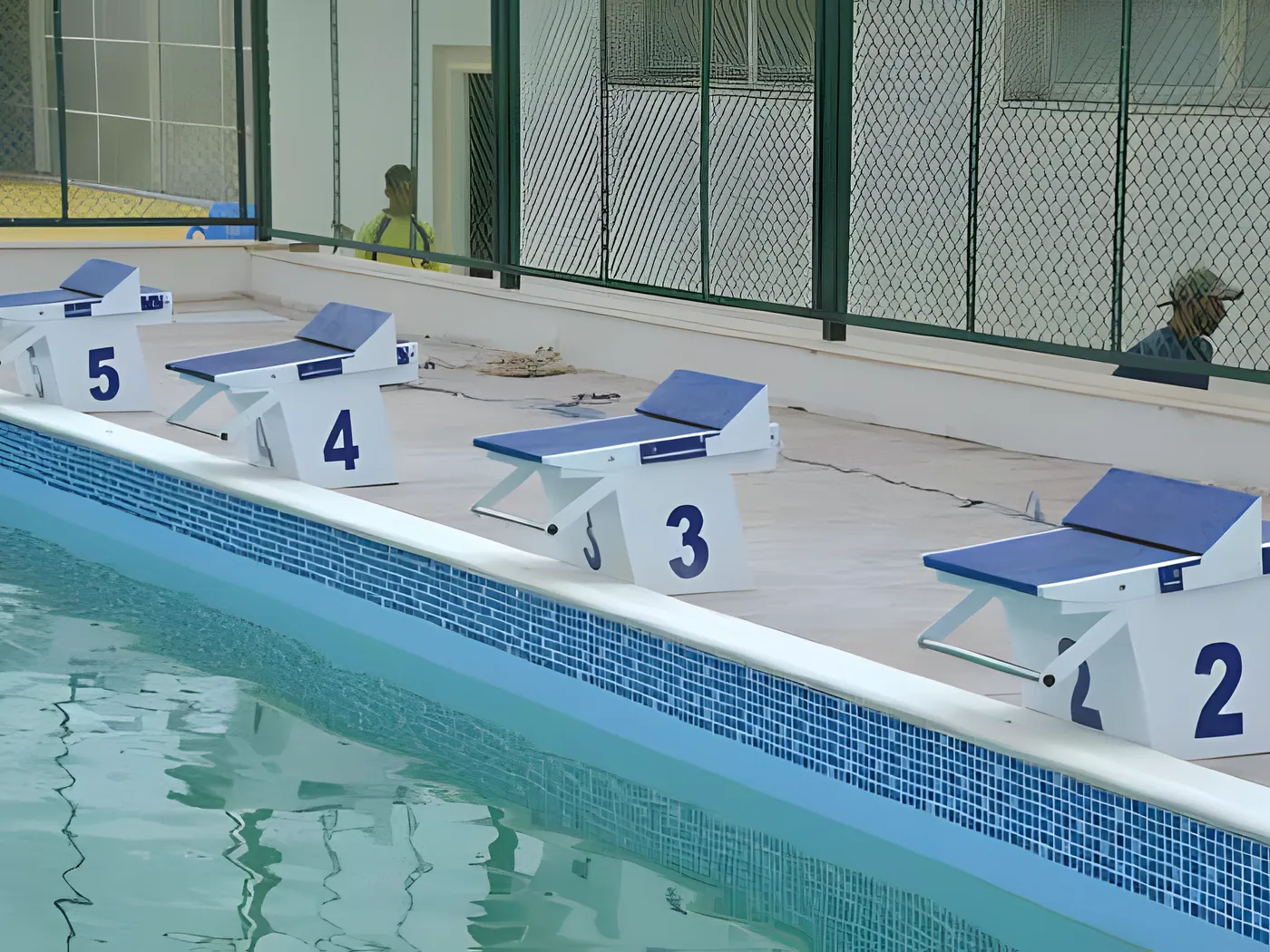 Numbered starting blocks along the deck of a covered competition pool